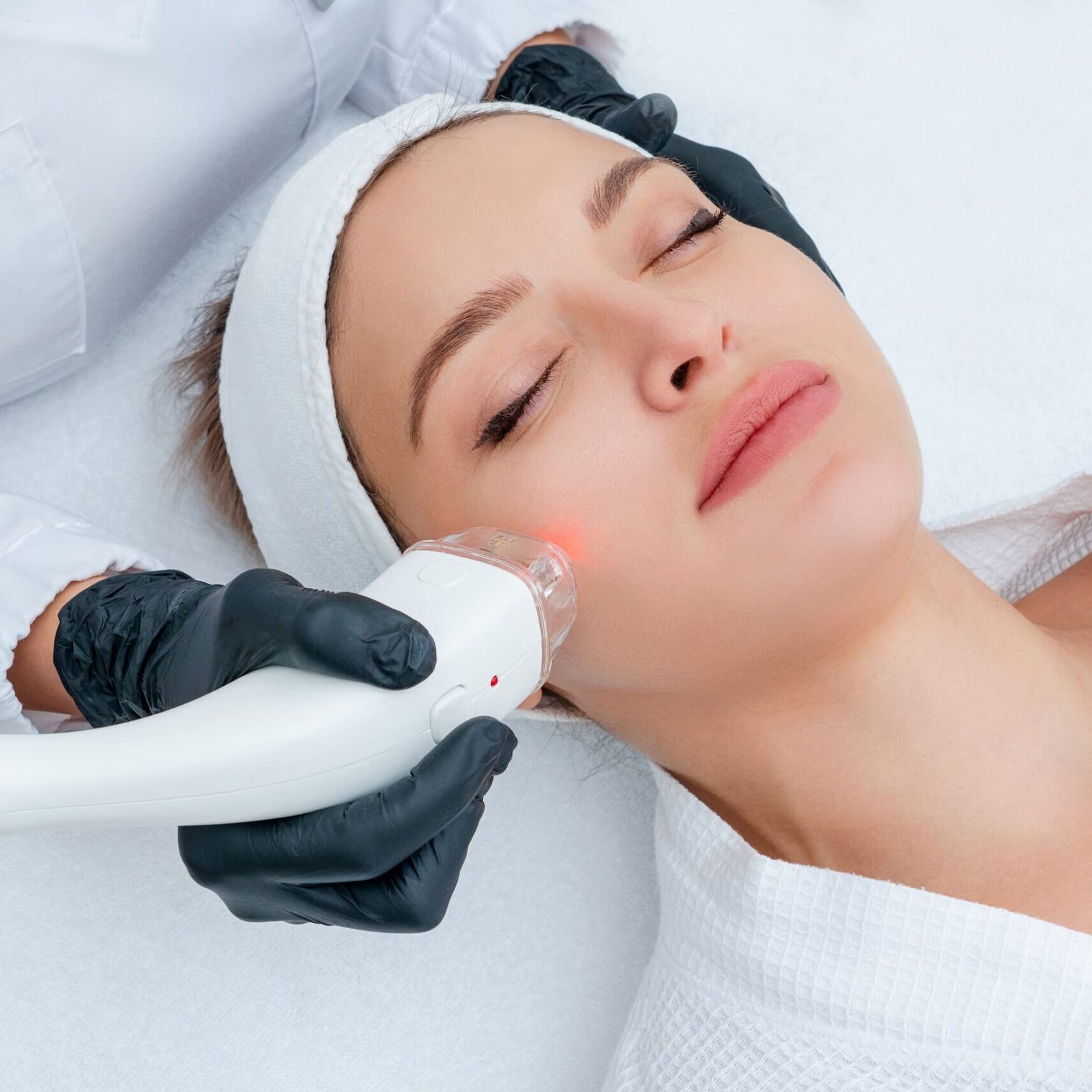 A woman getting her face cleaned with an electric device.