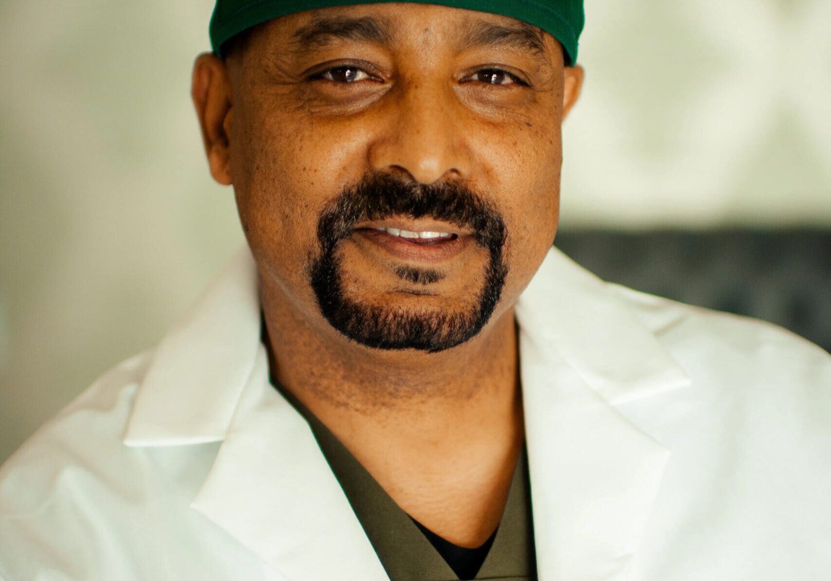 A man in white lab coat and green hat.